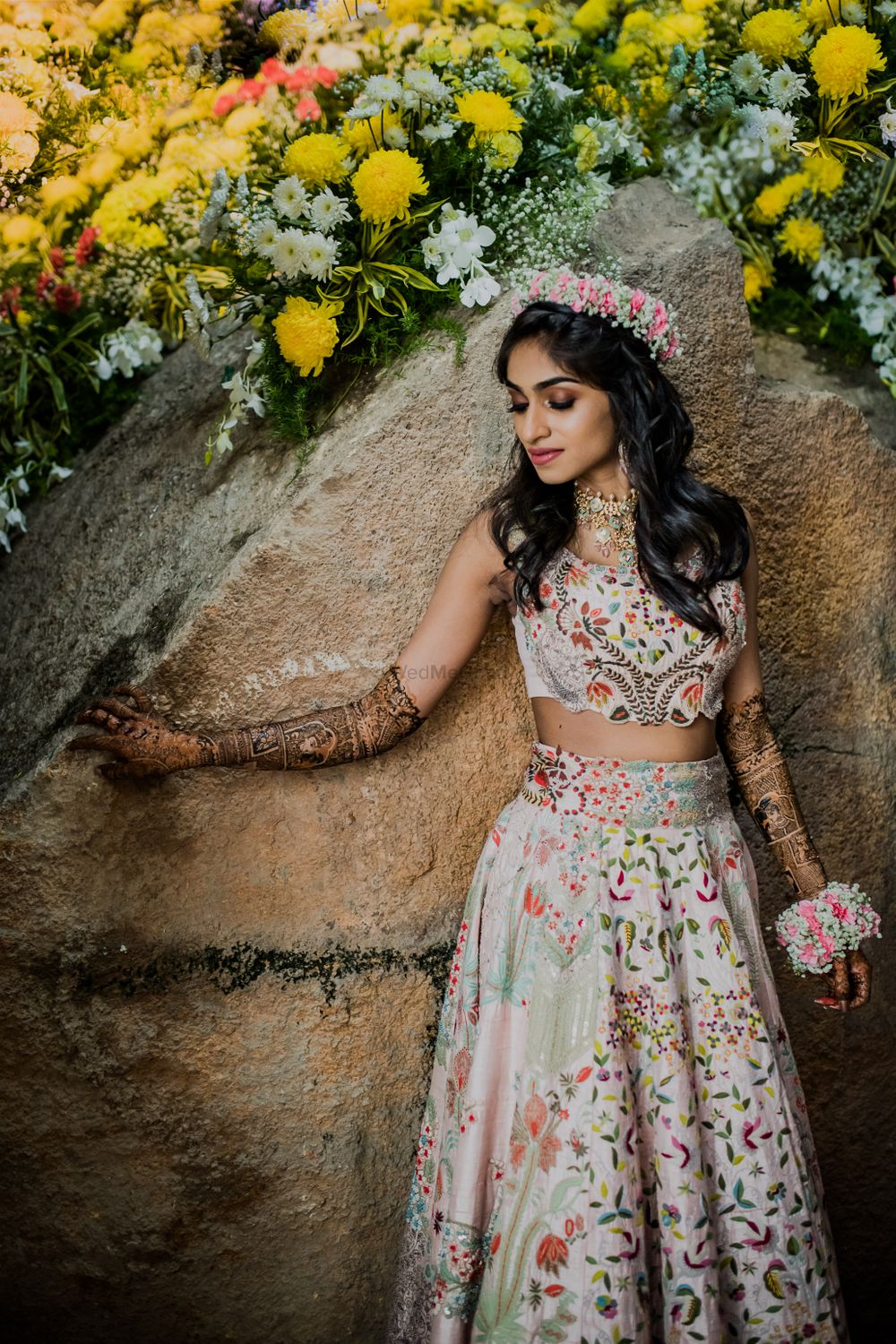 Photo of A bride in a tiara and floral jewellery for her mehndi