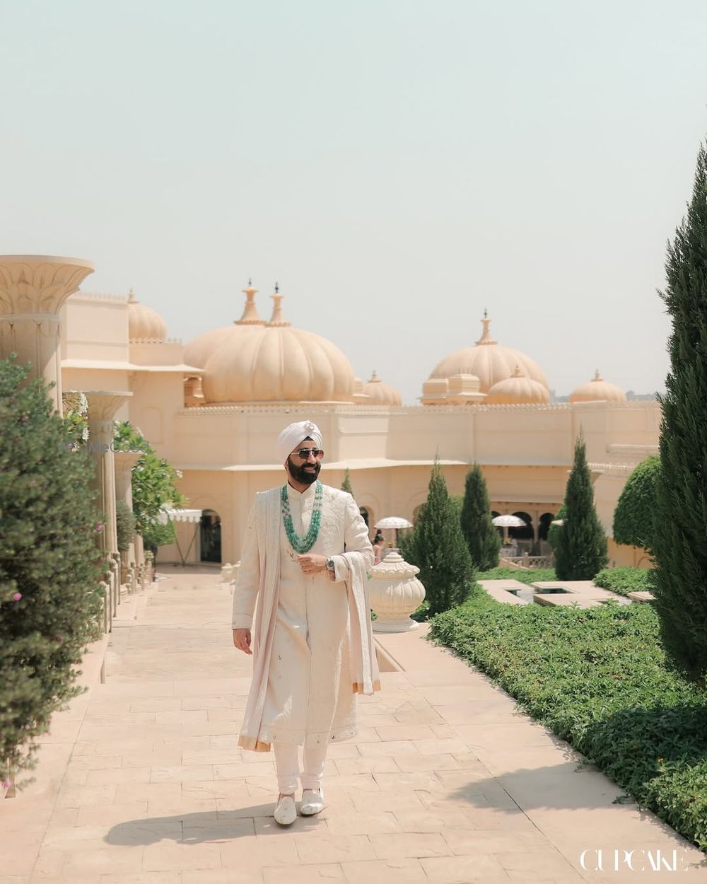 Photo of Punjabi grooom in a ivory sherwani and emerald jewellery