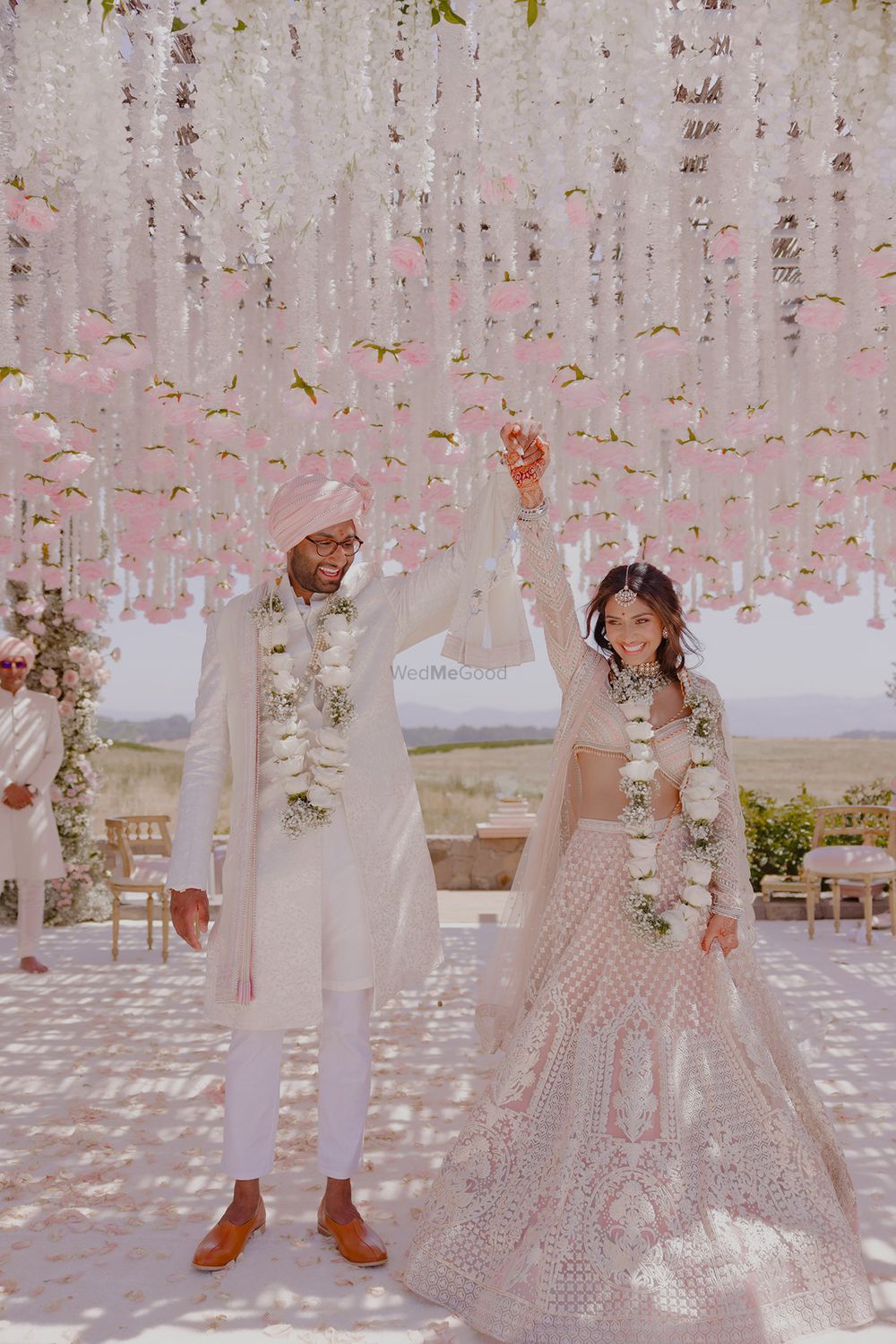 Photo of Happy just-married couple portrait with mandap decor in white and pink