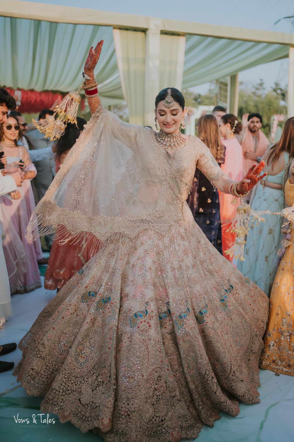Photo of Fun twirling shot of the bride in a stunning pastel lehenga with peacock detailing on her wedding day