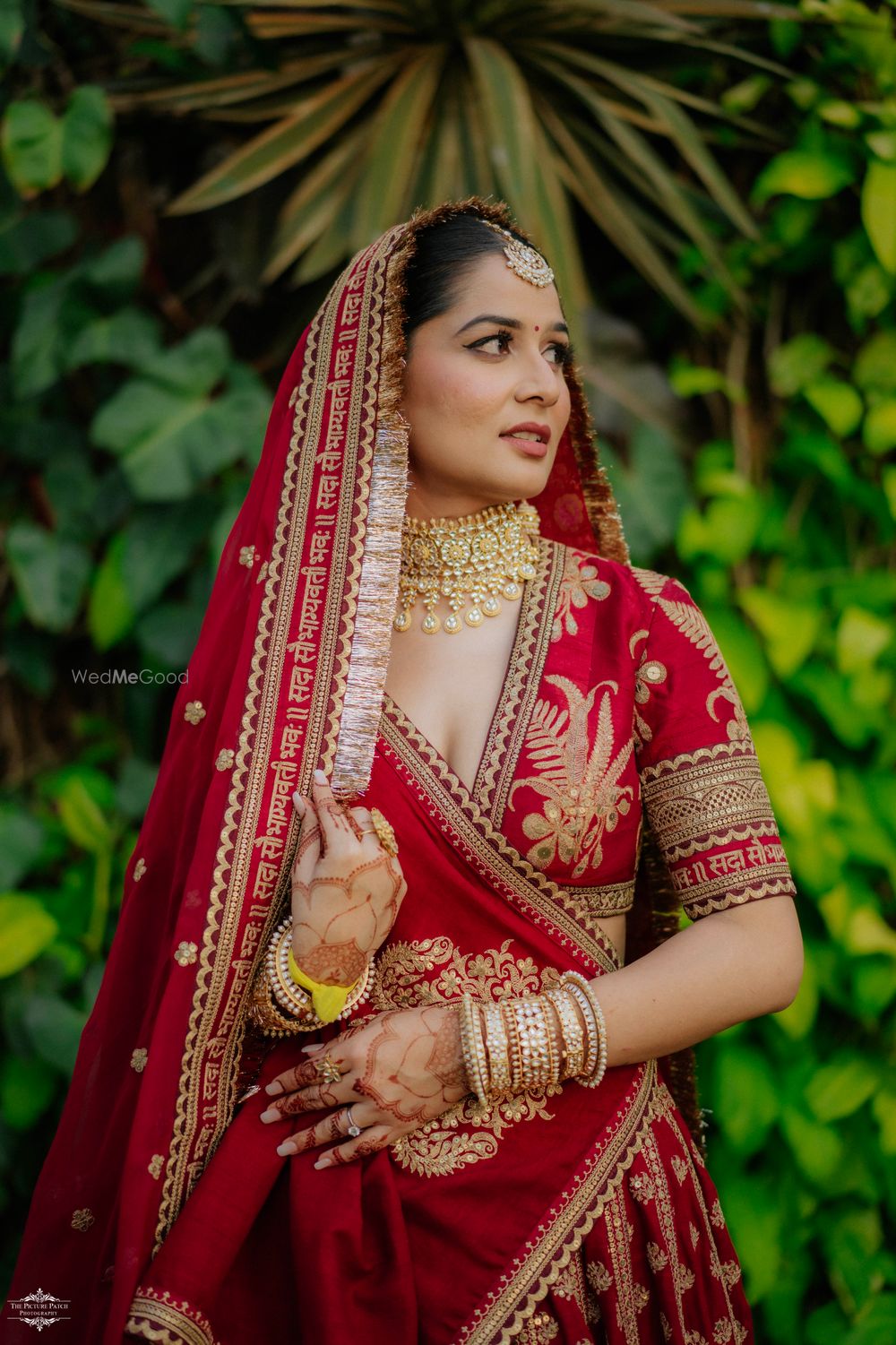 Photo of Classic bridal portrait in a red and gold Sabyasachi lehenga and a unique tasseled dupatta with inscription on it
