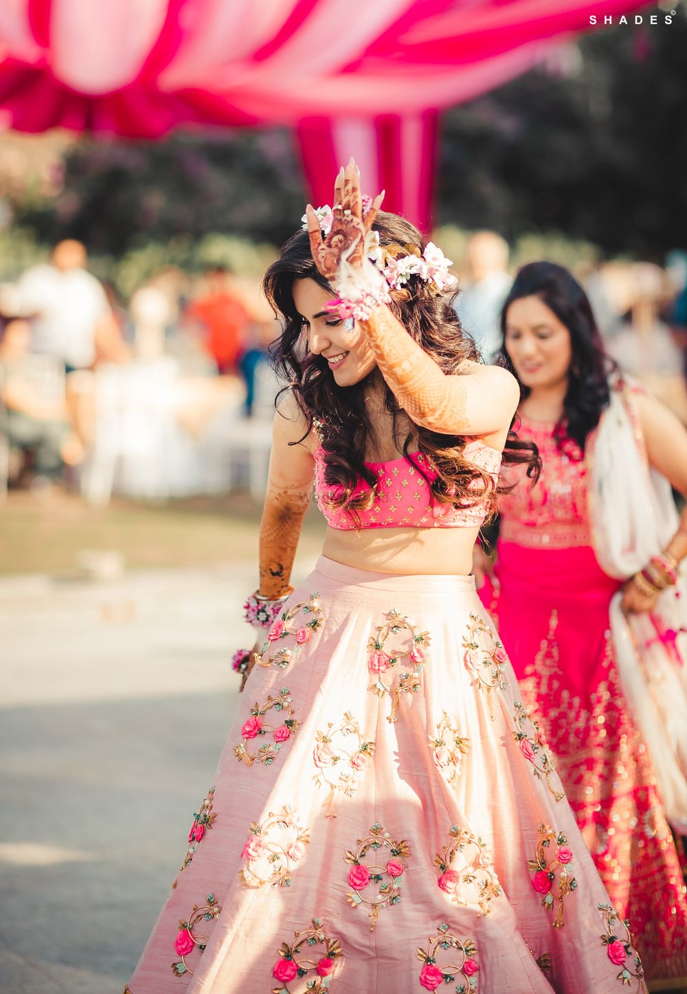 Photo of A bride in a pink lehenga and floral jewellery for her mehndi ceremony
