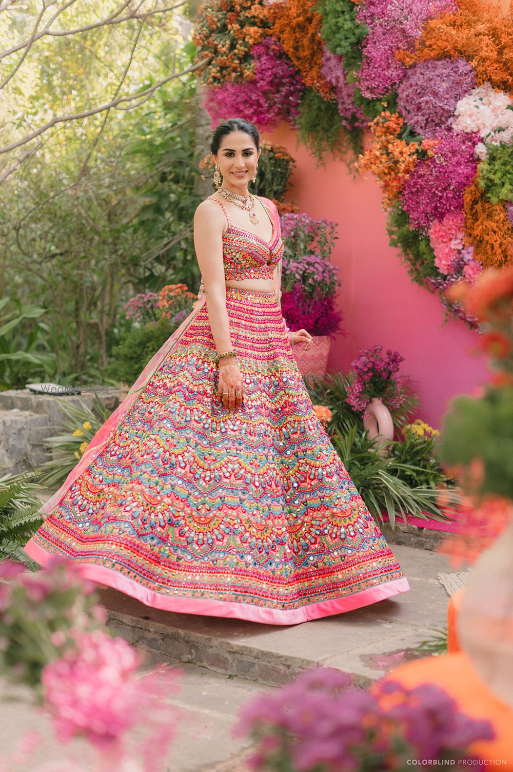 Photo of Stunning multi coloured mehendi lehenga and multi coloured floral decor for an outdoor mehendi event