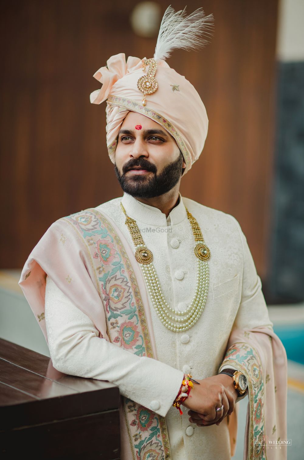 Photo of Groom wearing an ivory sherwani with a pink stole and safa.