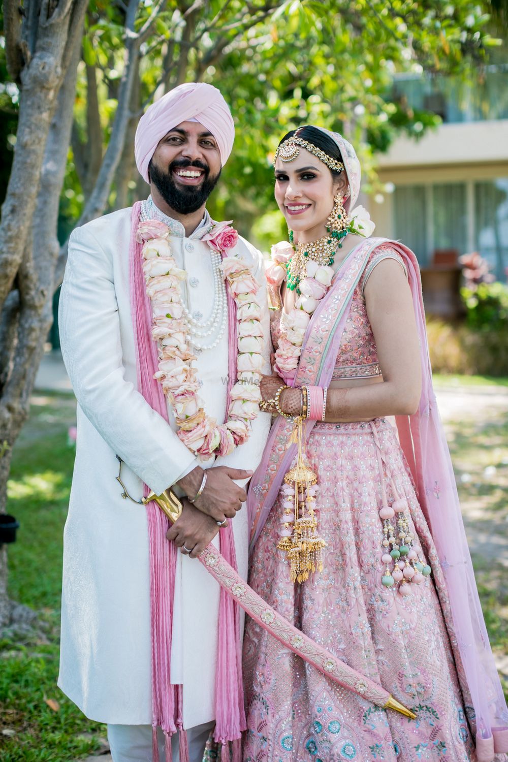 Photo of Bride and groom twinning in pastel pink outfits.