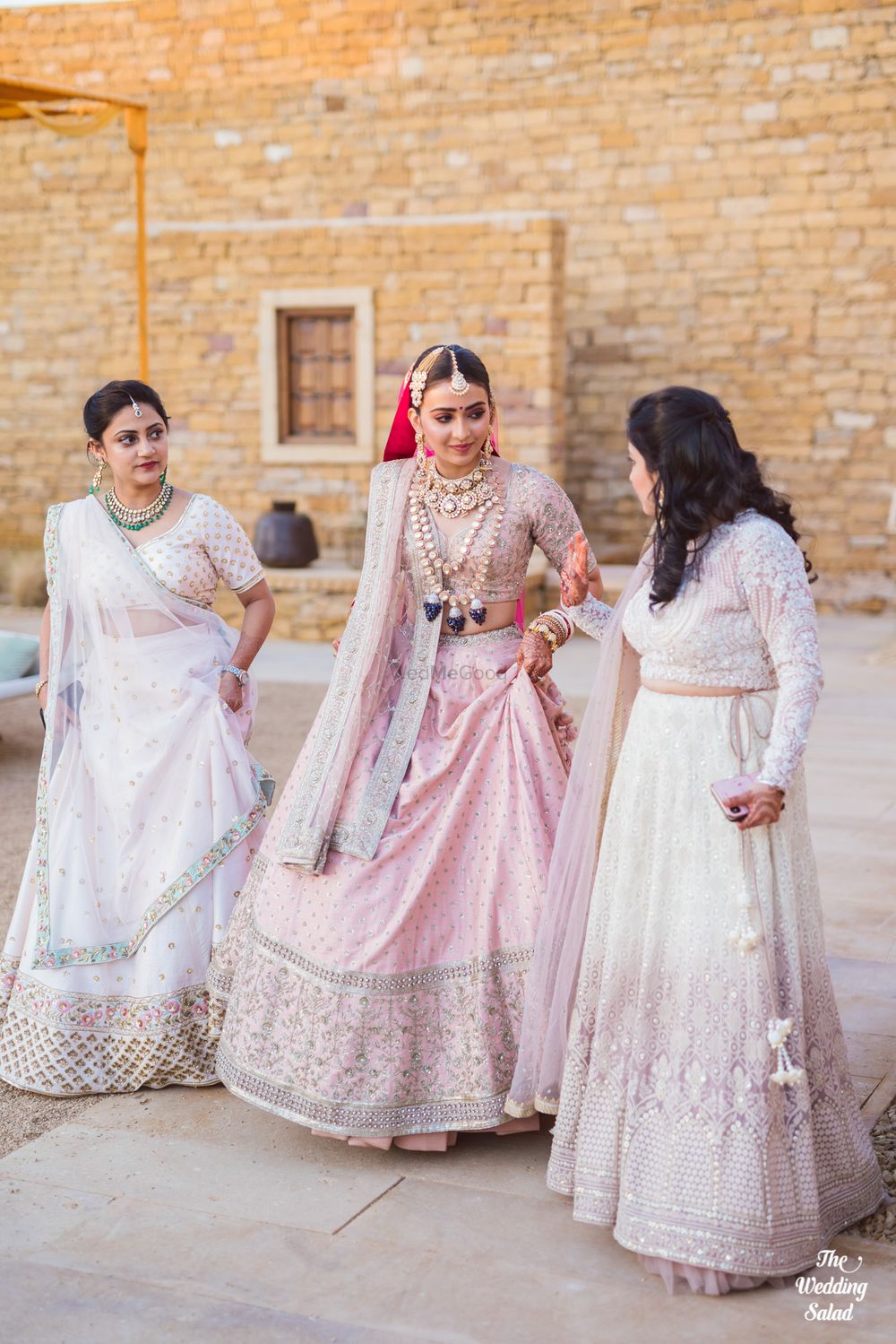 Photo of bride in a light pink lehenga with her bridesmaids matching in white