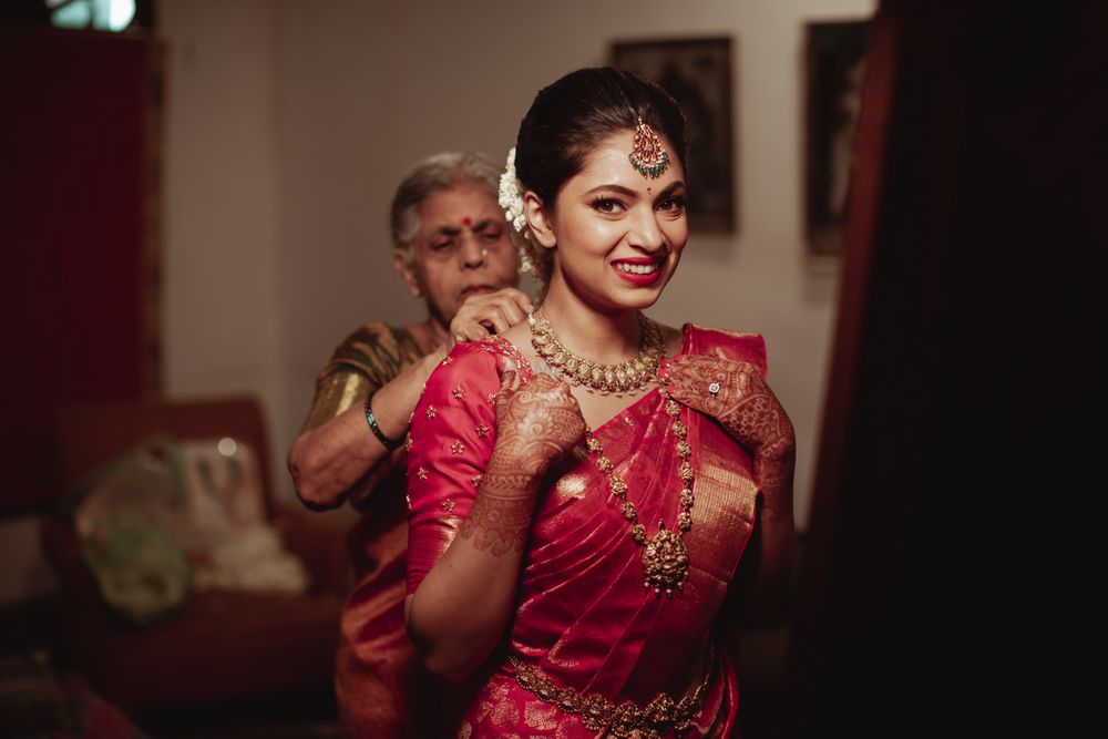Photo of Getting ready shot of a south indian bride dressed in a red & gold saree.
