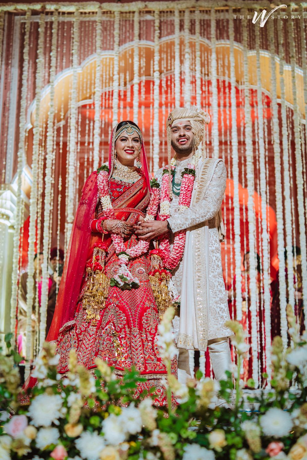 Photo of Bride and groom dressed in red and white respectively.
