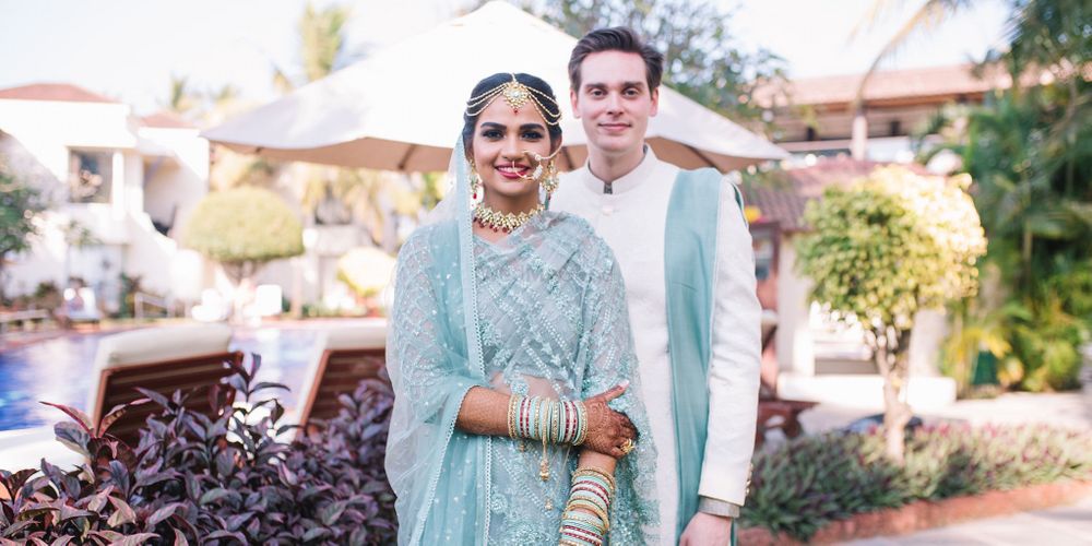 Photo of A bride and groom in coodinated blue outfits for their wedding