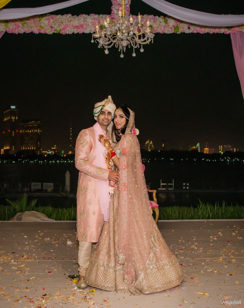 Photo of Light pink bride and groom sherwani