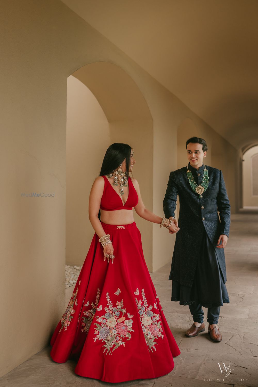 Photo of Candid couple capture on the wedding day with bride in a red lehenga and groom in a black sherwani