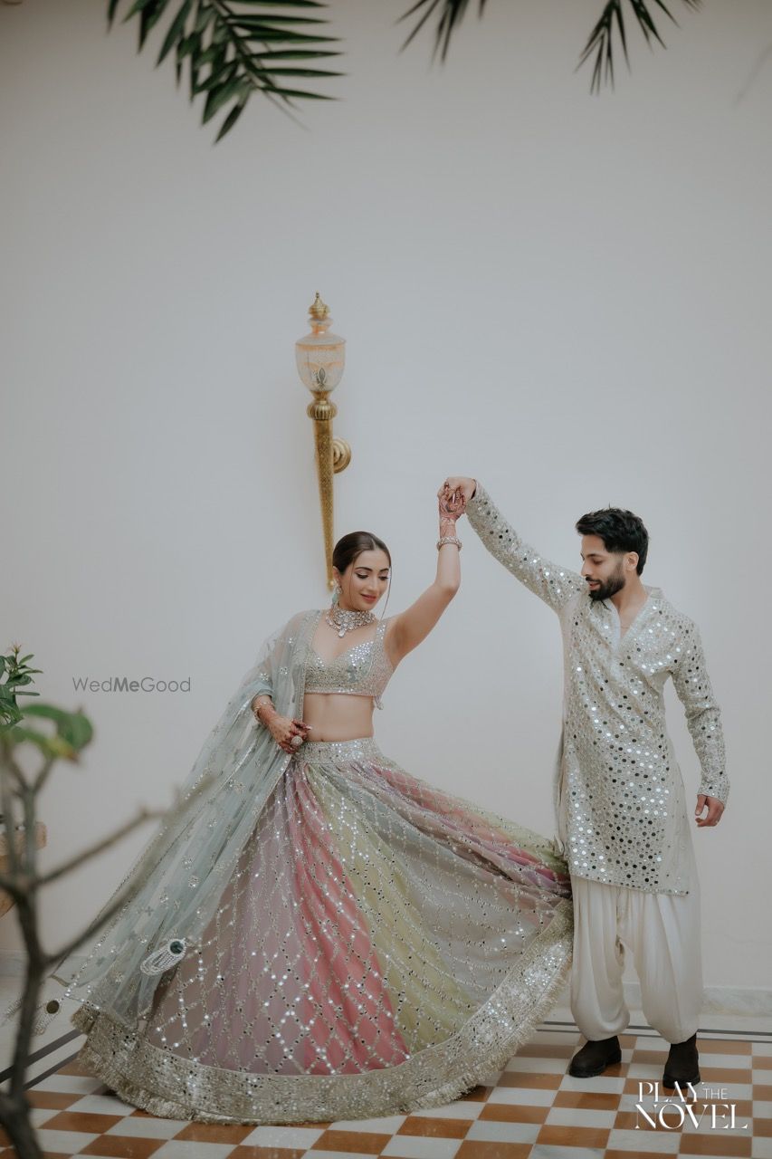 Photo of Groom twirling the bride on the mehendi day with both in sparkling outfits in silver