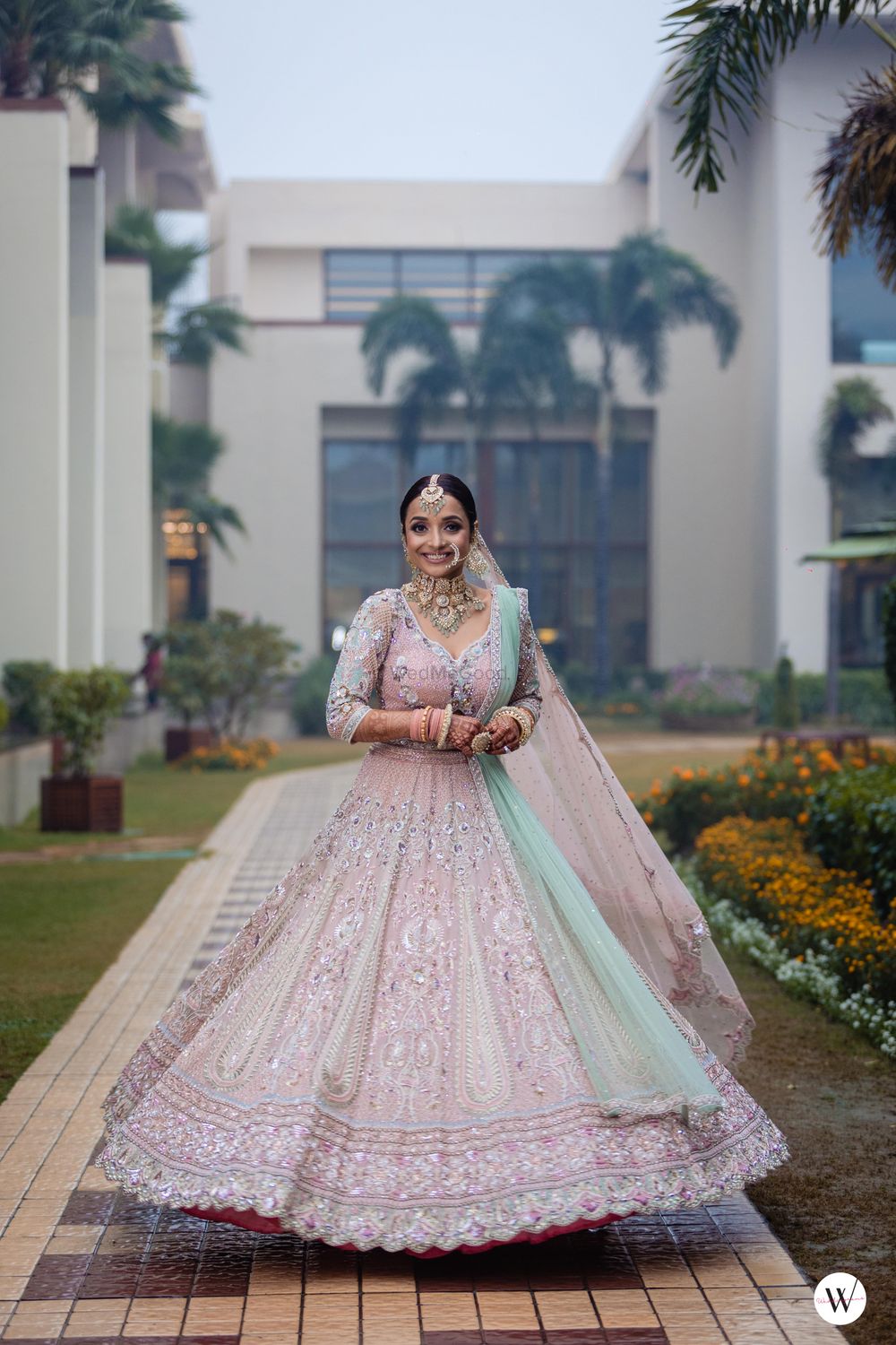 Photo of bride twirling in a beautiful pastel lehenga with contrasting dupatta