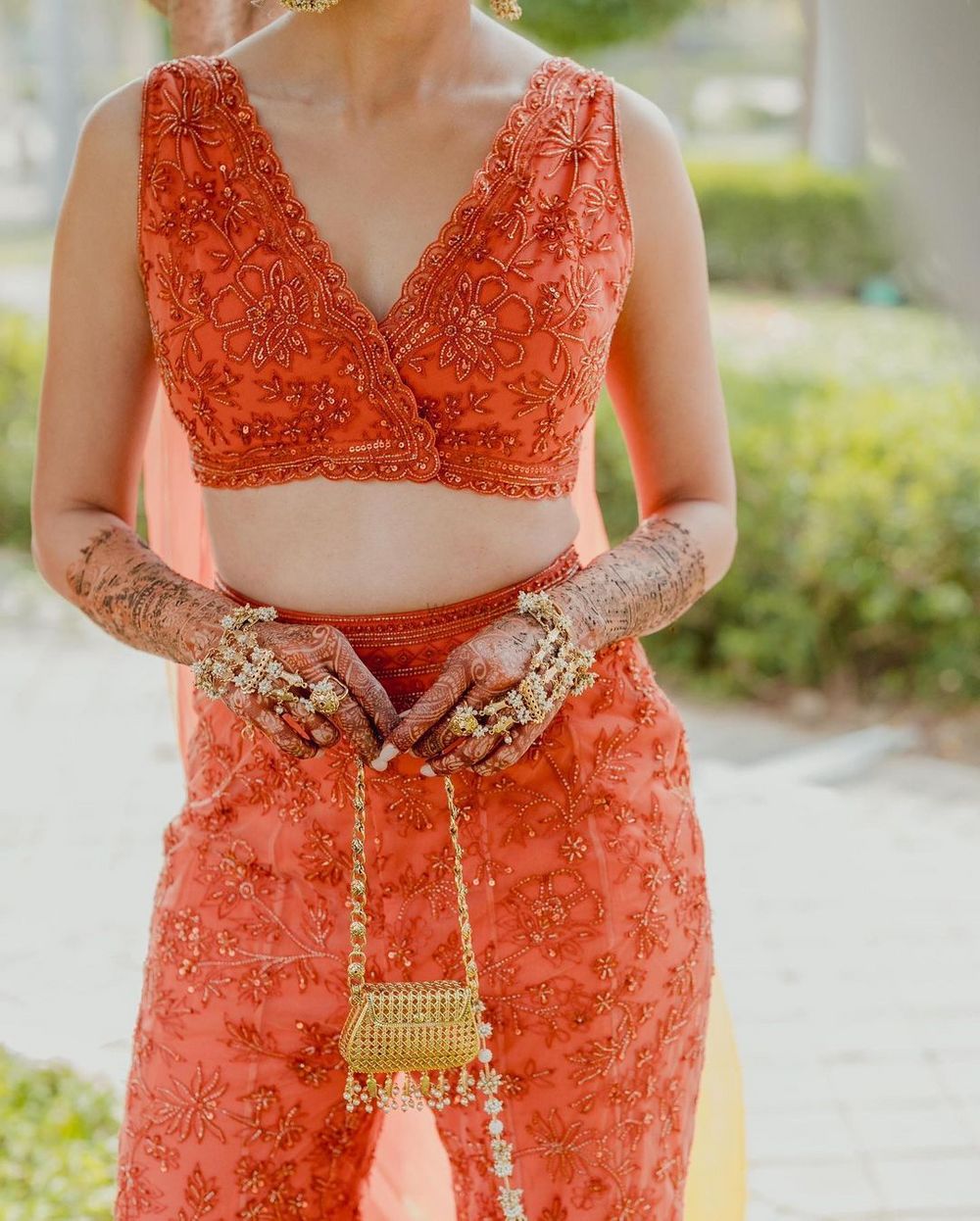Photo of Cute shot of the bride carrying a mini gold bag with a closeup of the gold haathphool