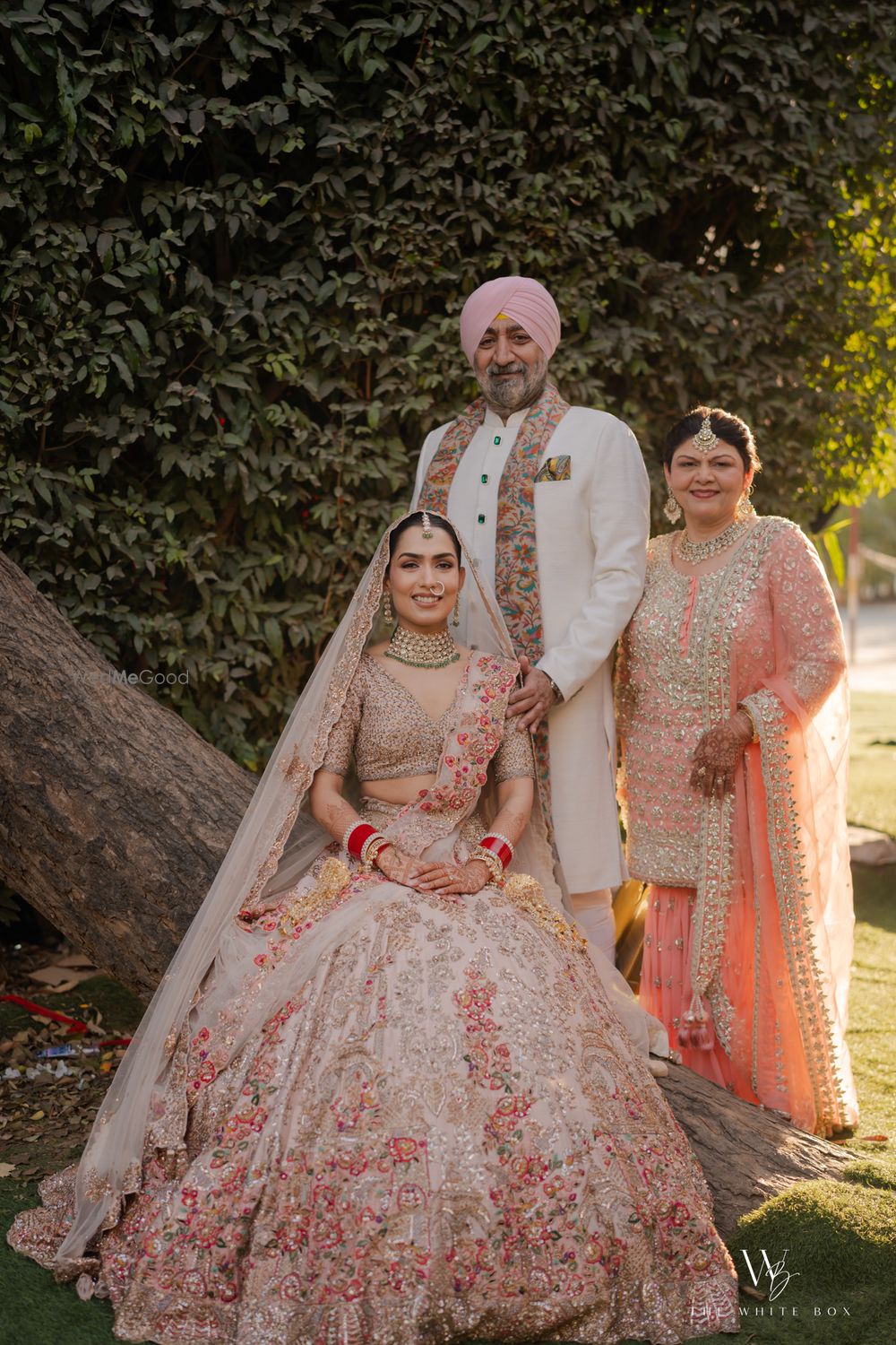 Photo of Lovely capture of the bride on the wedding day with her parents in an outdoor venue