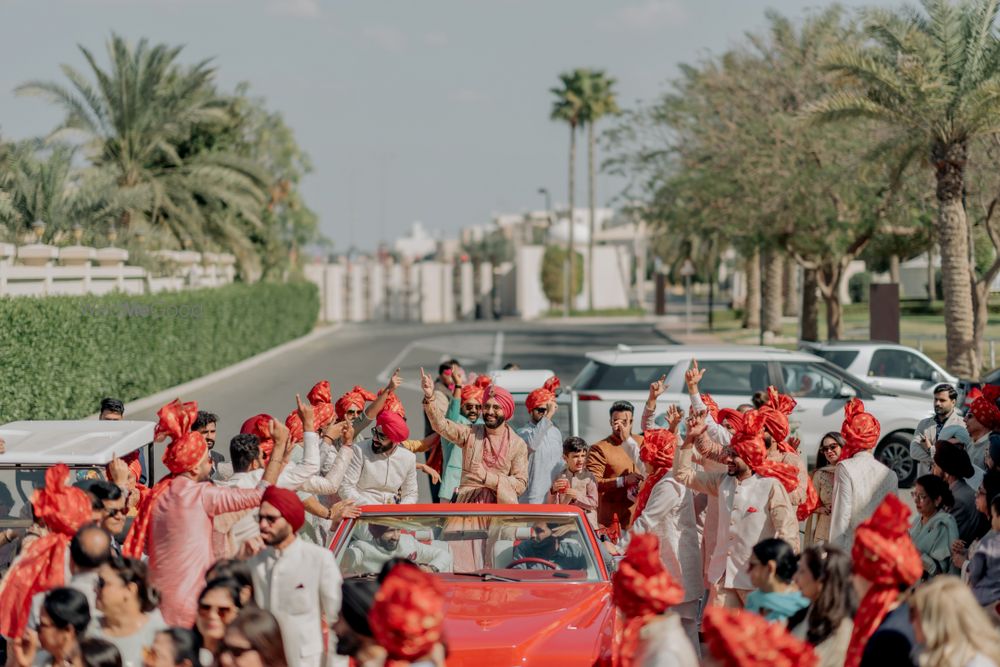 Photo of Baraatis entry with the groom in all co-ordinated red safas and a red vintage car