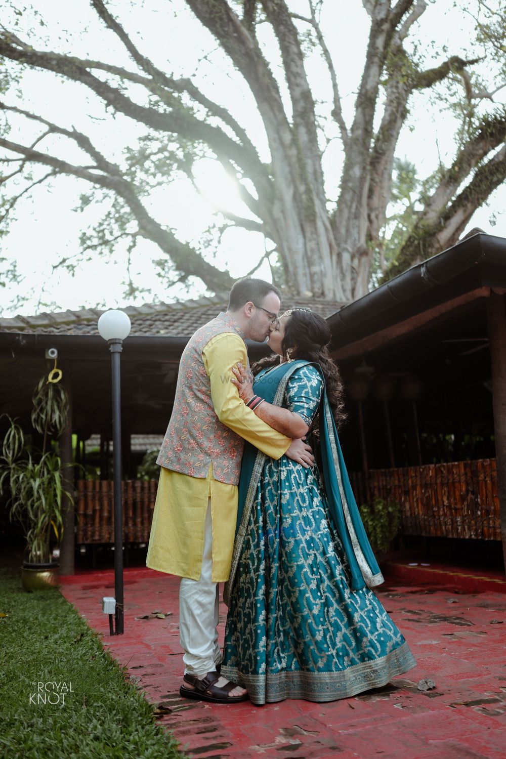 Photo of couple kissing shot with bride in customised mehendi lehenga