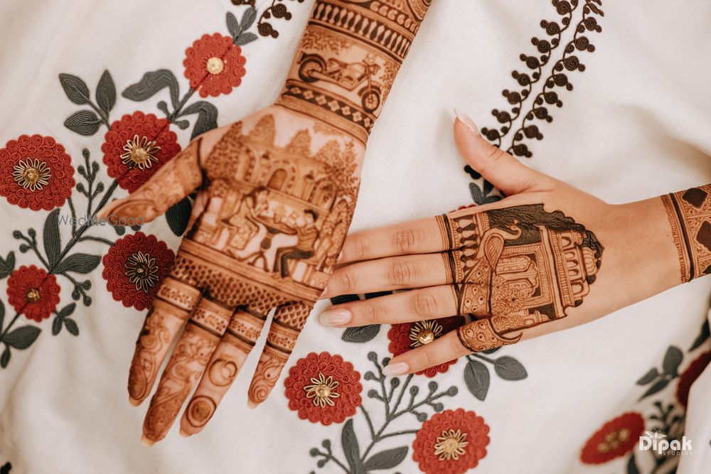 Photo of Unique mehendi design with the couple portrait and a minimal back of the hand mehendi