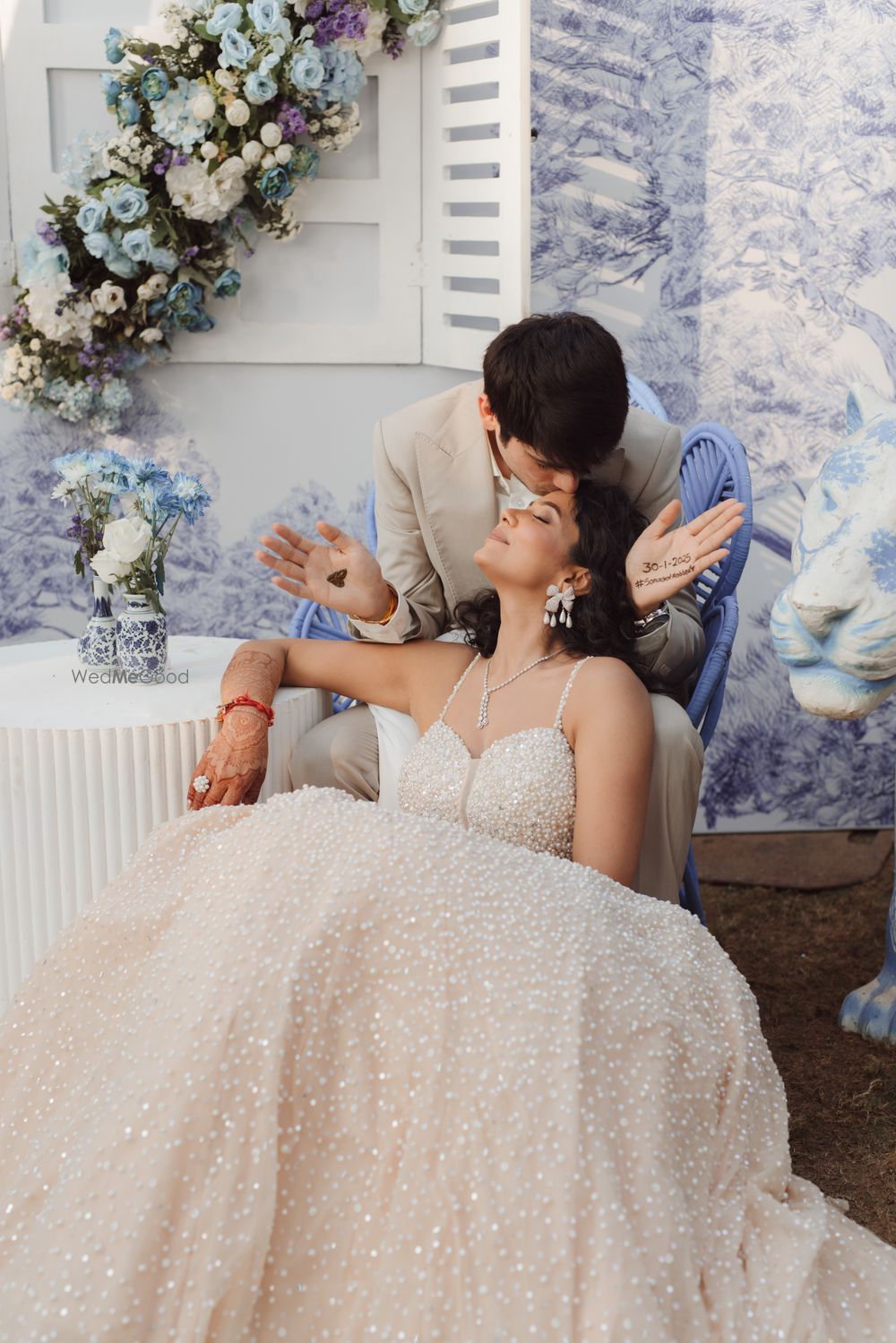 Photo of Lovely shot of the groom kissing the bride in a sparkly nude gown for the mehendi