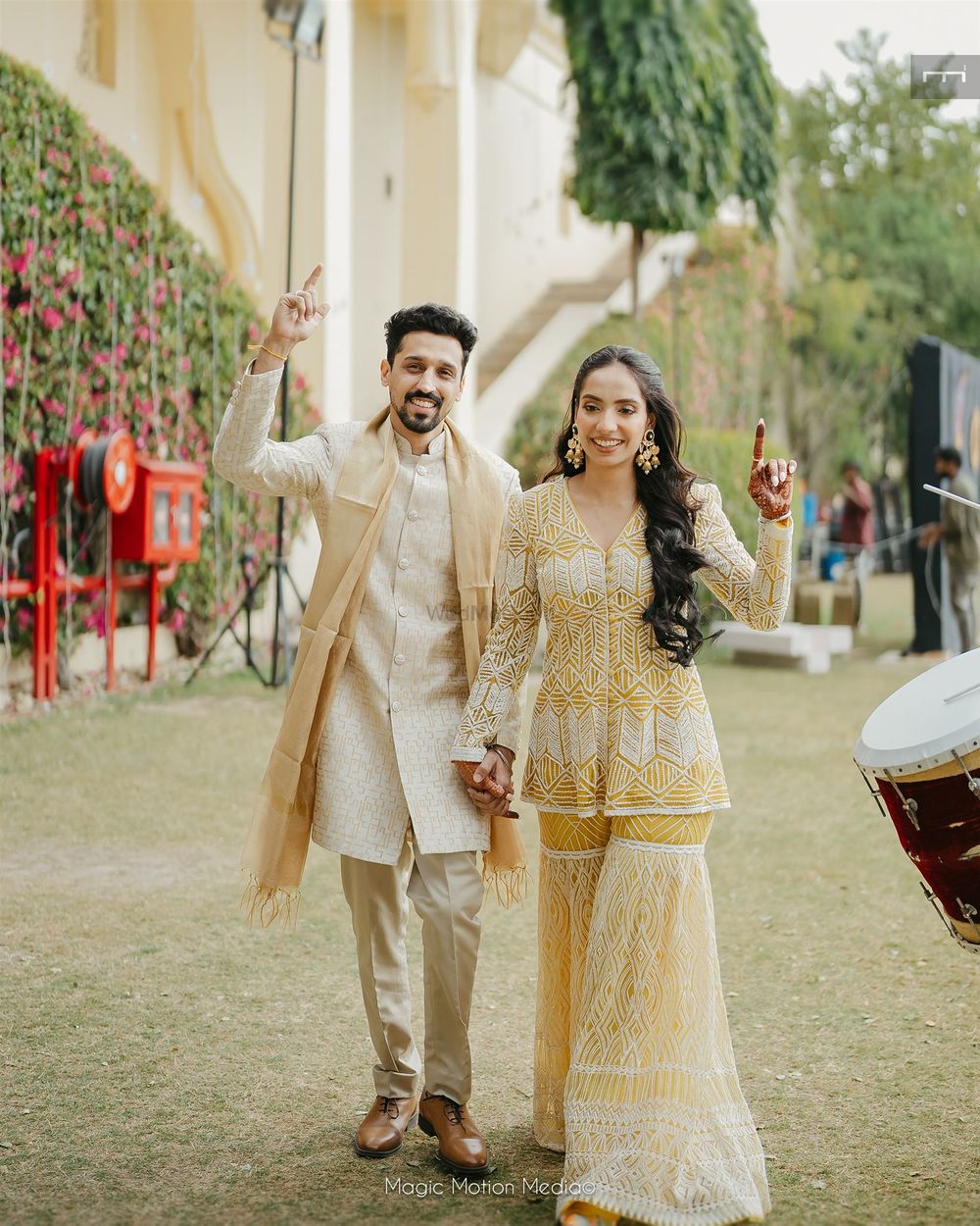 Photo of Fun couple entry shot with bride and groom in matching yellow and ivory outfits