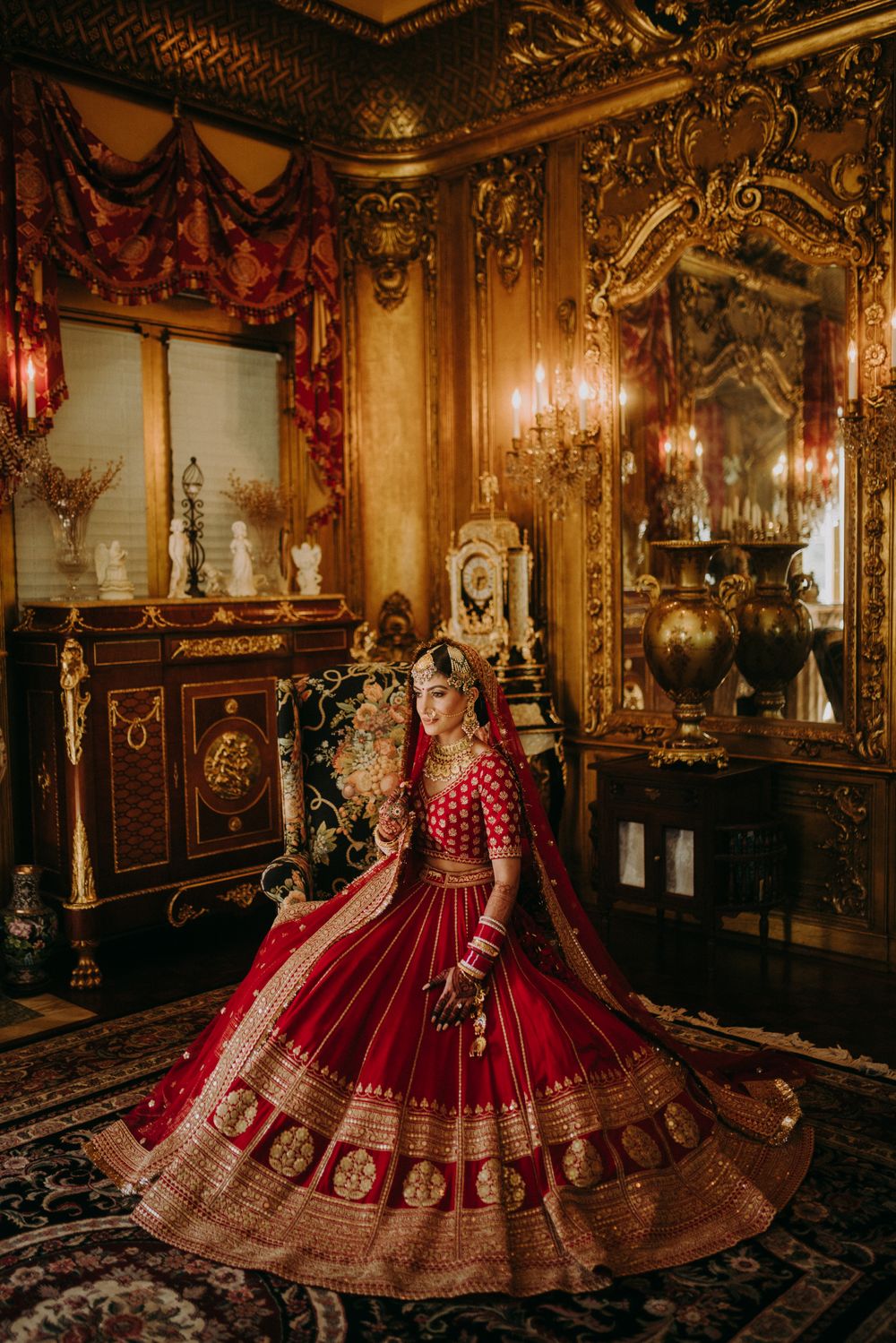 Photo of bride wearing a red and gold sabya lehenga with regal vibes