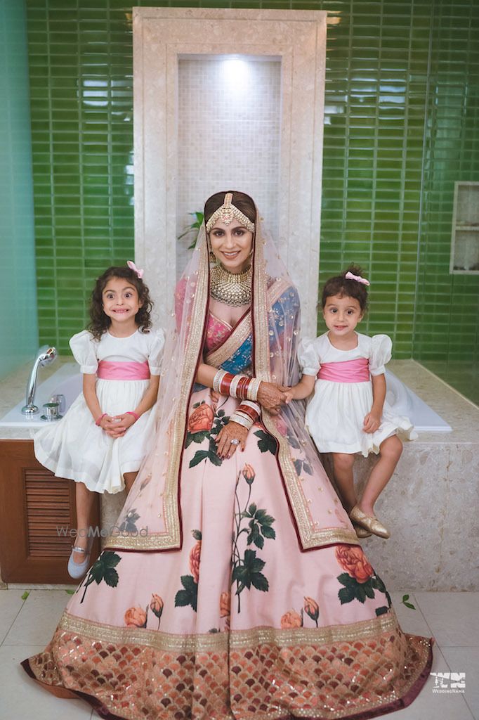 Photo of Bride wearing floral print sabya lehenga with flower girls