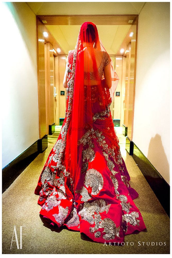 Photo of Red Manish Malhotra bridal lehenga trailing