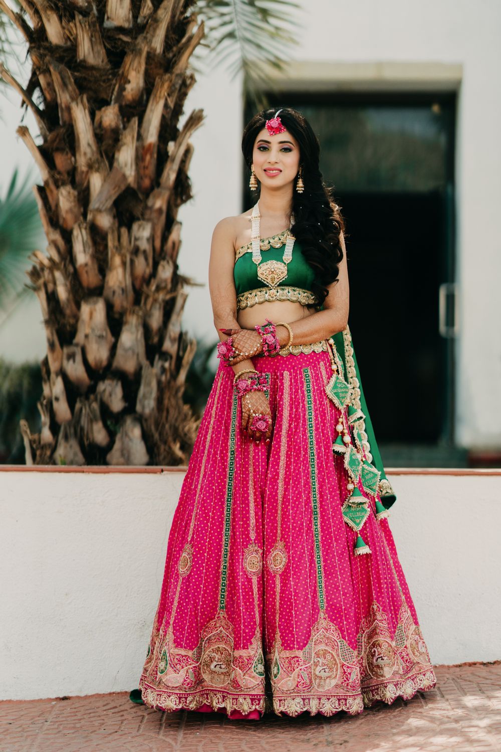 Photo of Bride wearing a green one-shoulder blouse with a pink lehenga.