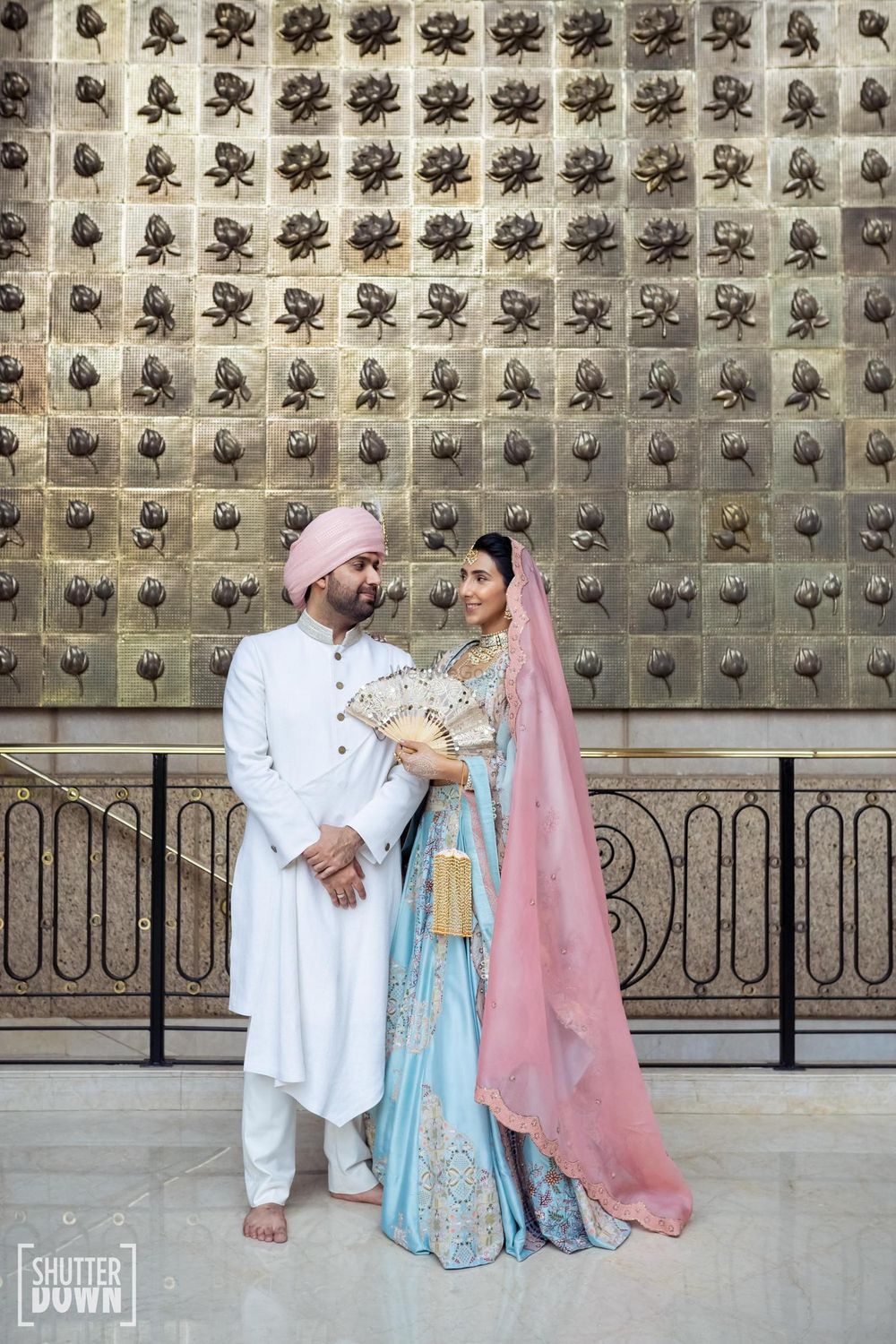 Photo of Wedding day couple shot with the groom in an ivory sherwani and the bride in a pastel lehega.