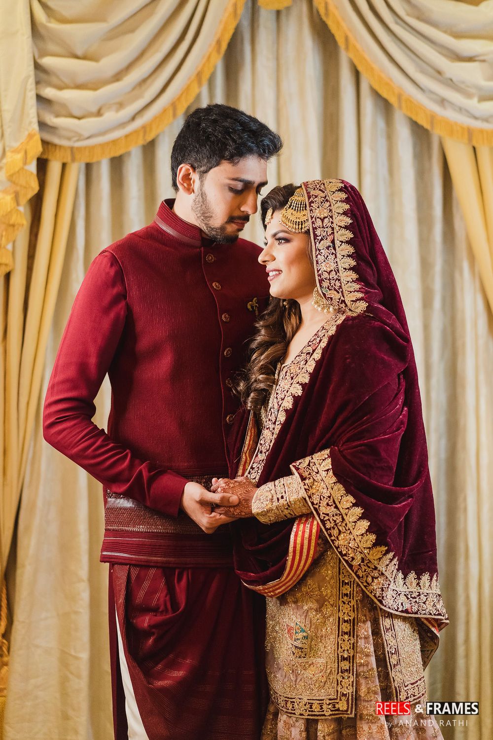 Photo of A couple in coordinated maroon outfits for their wedding festivities