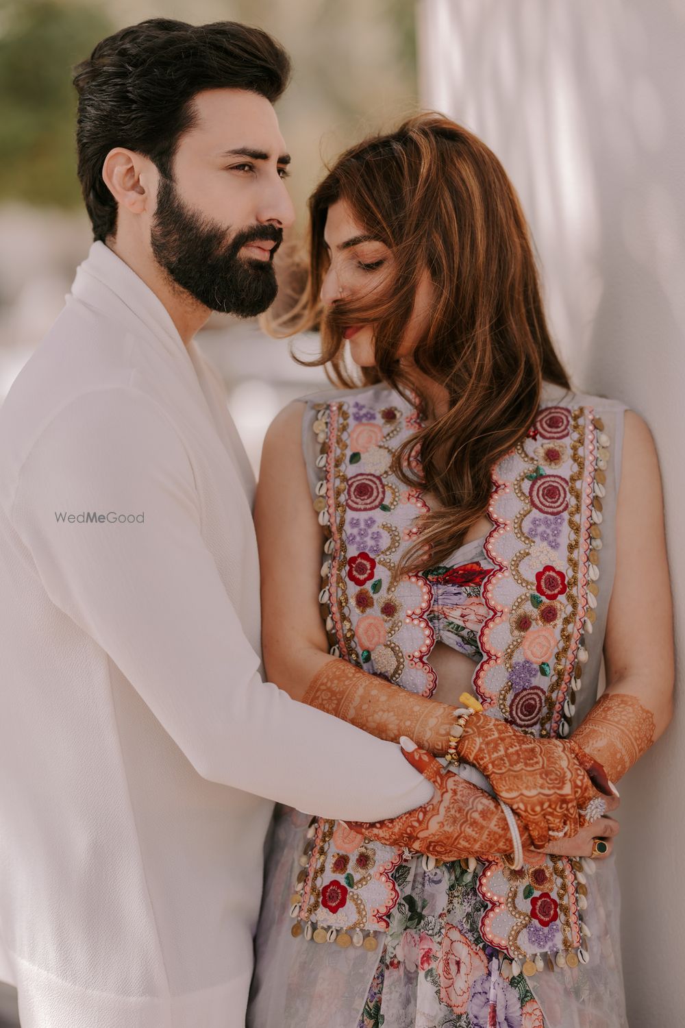 Photo of Lovely couple shot with a bride in a gorgeous floral jacket and the groom in an all-white ensemble.