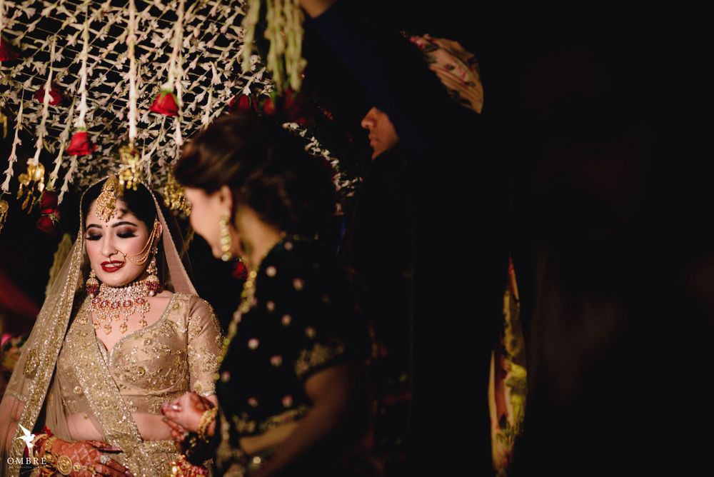 Photo of A bride in a gold lehenga entering under a phoolon ki chaadar