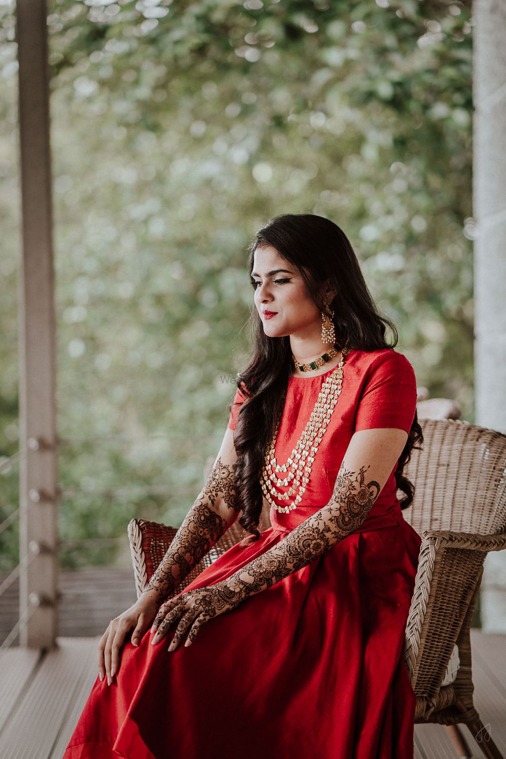 Photo of simple mehendi outfit in red with bridal mehendi on hands