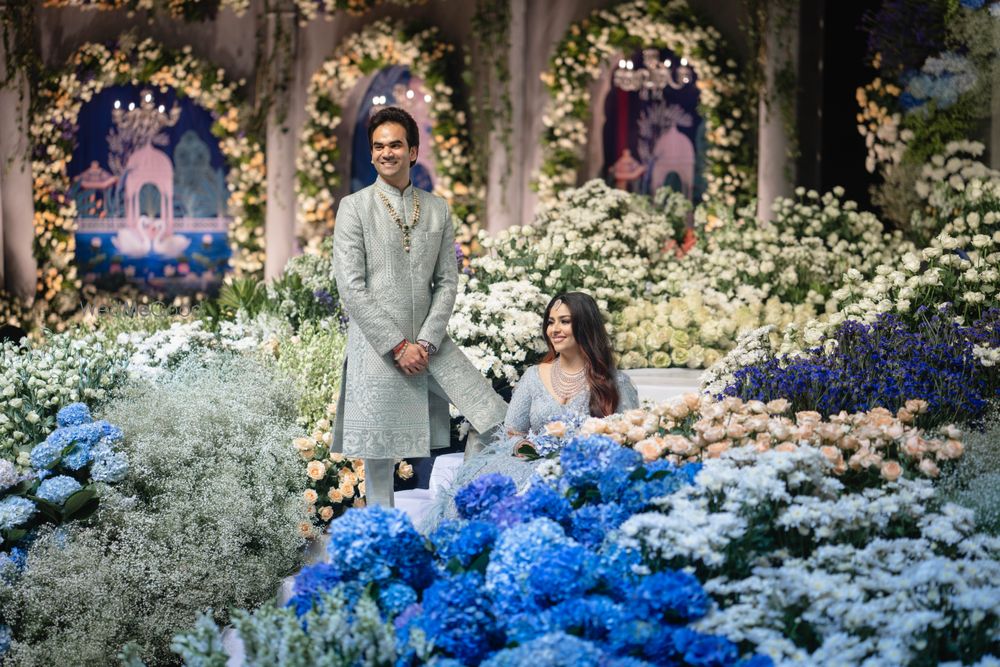 Photo of Stunning floral decor with shades of blue and white with the couple standing amongst the flowers