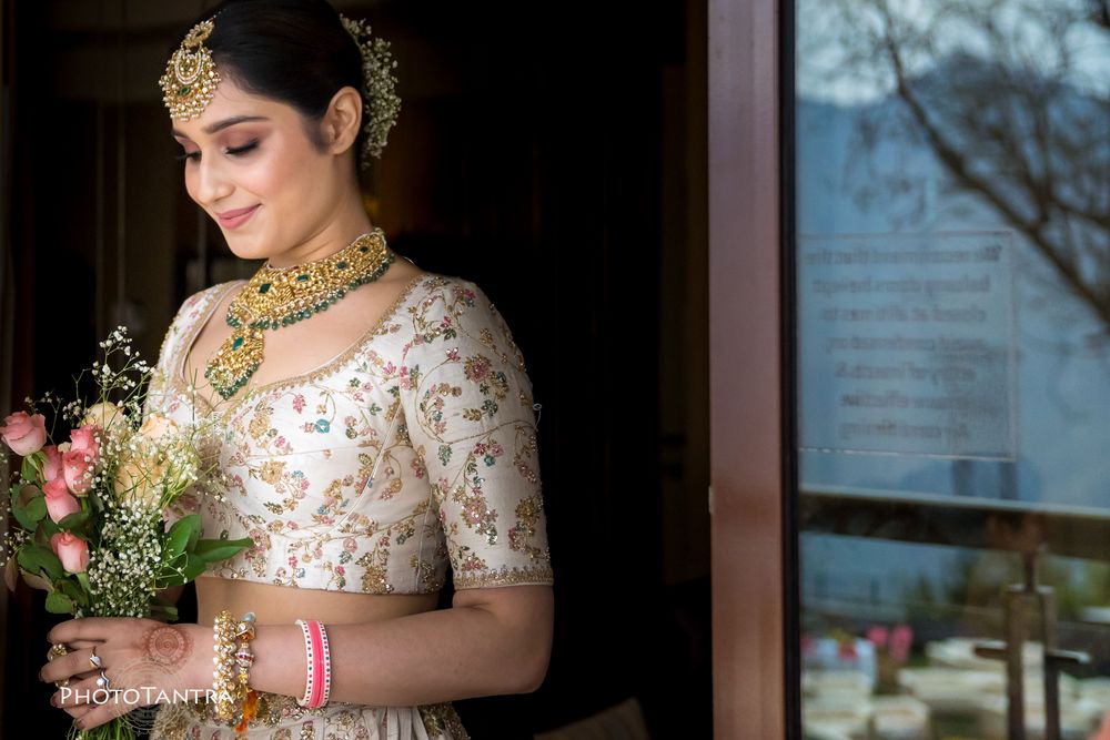 Photo of A closeup shot of a bride in an ivory lehenga