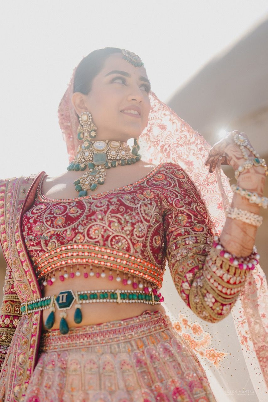Photo of Stunning bridal portrait with the bride in a heavy bridal red blouse with contrast emerald jewellery and a belt