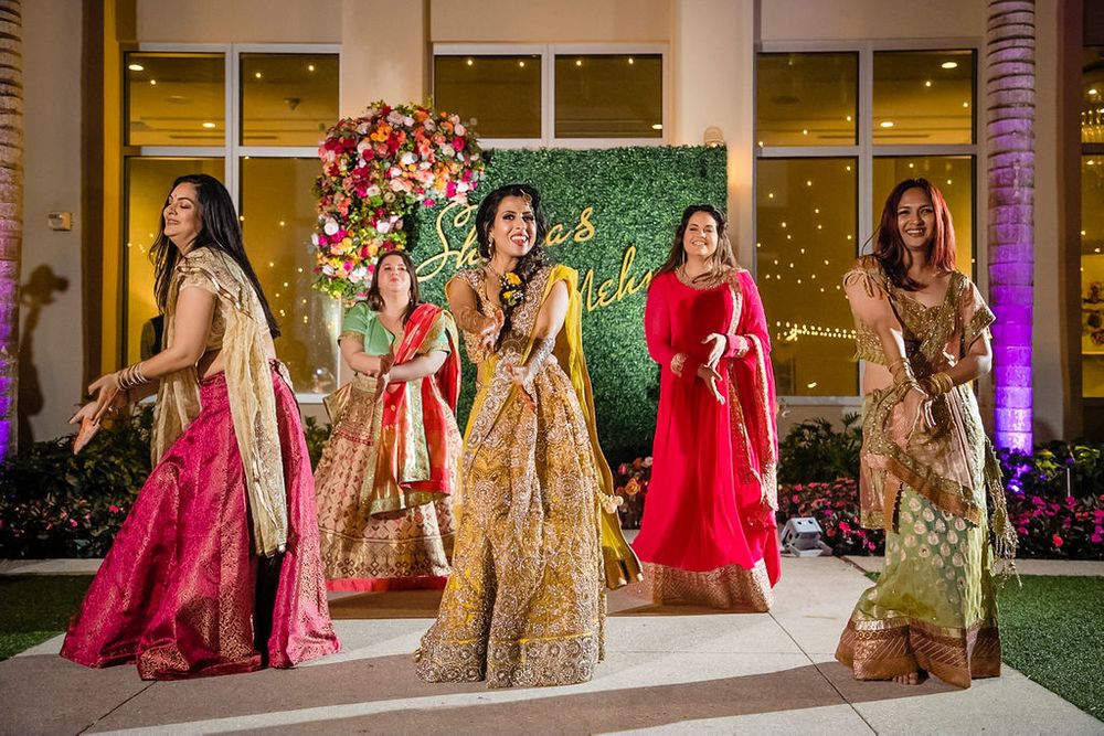 Photo of Bride and bridesmaids dancing on mehendi together