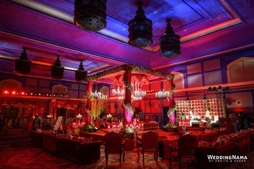 Photo of red mandap indoors with chandeliers hanging