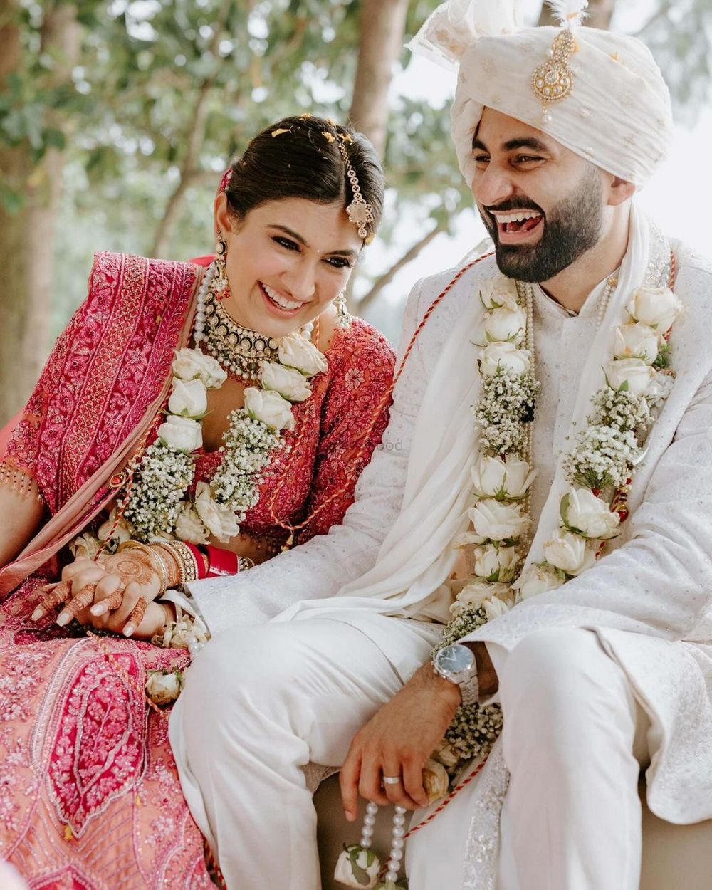 Photo of Bright and happy couple shot wearing ivory and babys breath jaimalas