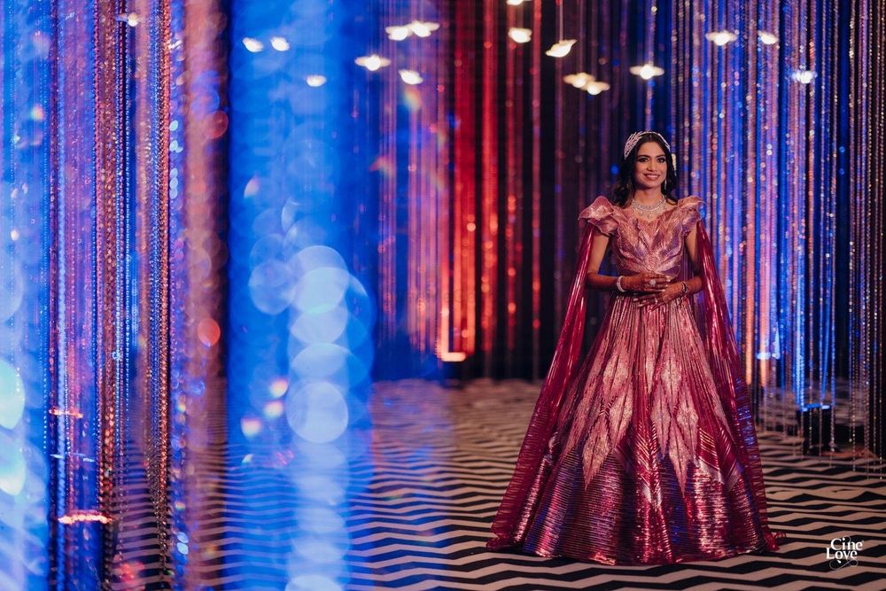 Photo of Bride wearing a metallic pink lehenga with a cape-sleeved blouse