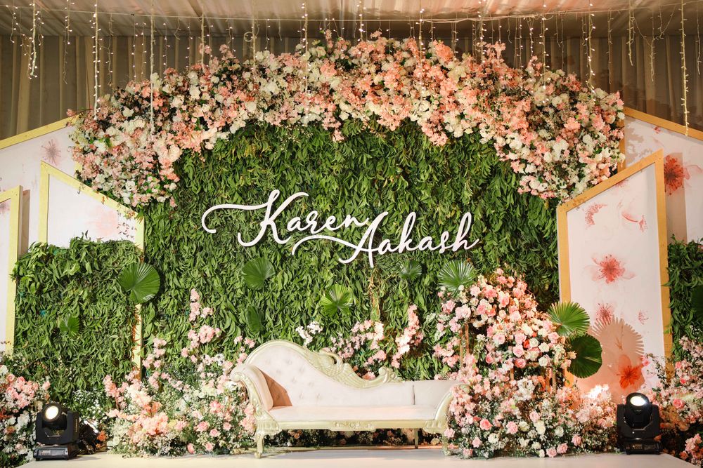 Photo of Beautiful stage decor for reception with a stunning personalised backdrop.