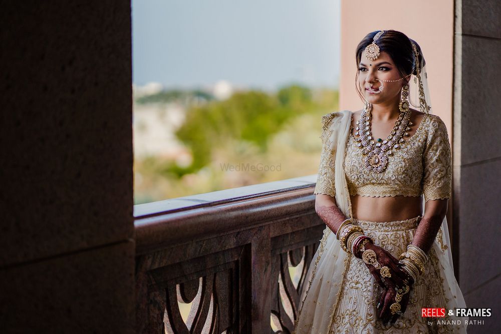 Photo of A bride in an ivory and gold lehenga with stunning jewelry on her wedding day
