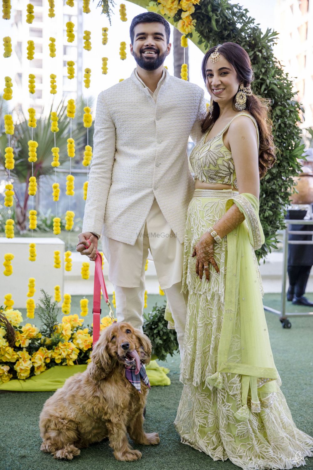 Photo of Bride and groom posing with their pet on Mehendi.