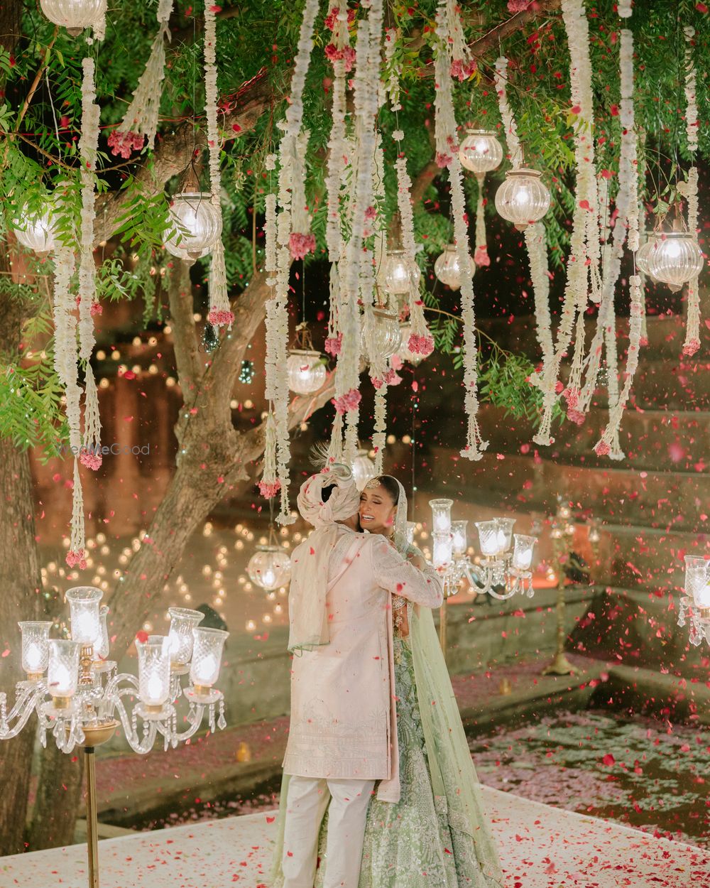 Photo of Bride and groom happy varmala photo with a tree mandap with lights and florals