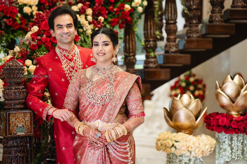 Photo of Gorgeous south indian couple portrait with bride in peach red saree and the groom in a red sherwani