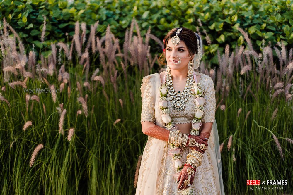 Photo of A bride in an ivory and gold lehenga with pastel jaimala