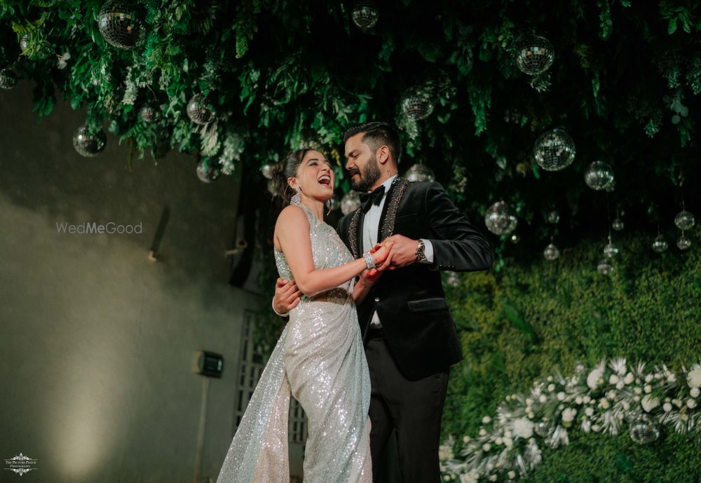 Photo of Fun capture of the bride and groom on their sangeet night in a silver saree and black tuxedo