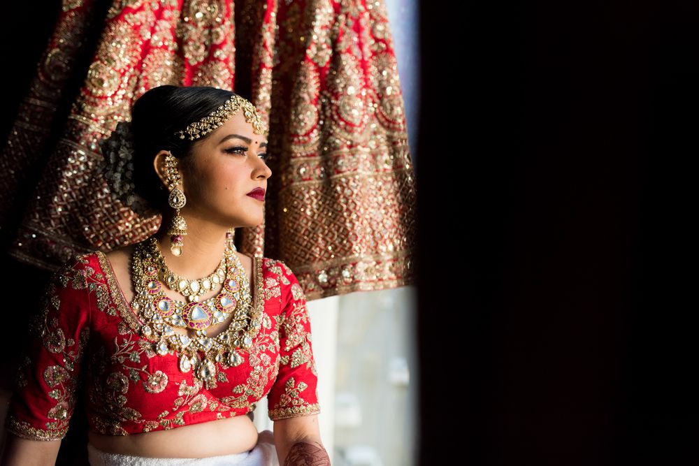 Photo of Getting ready bridal portrait with lehenga in backdrop