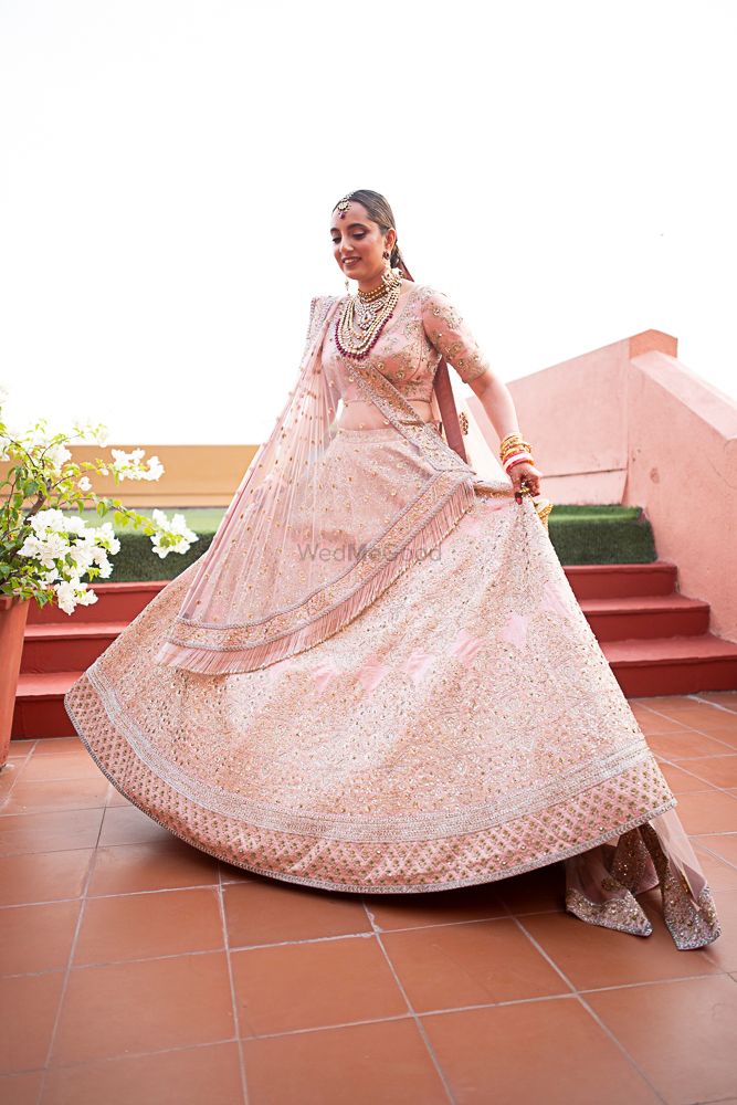 Photo of Bride dressed in pink lehenga posing on her wedding day.