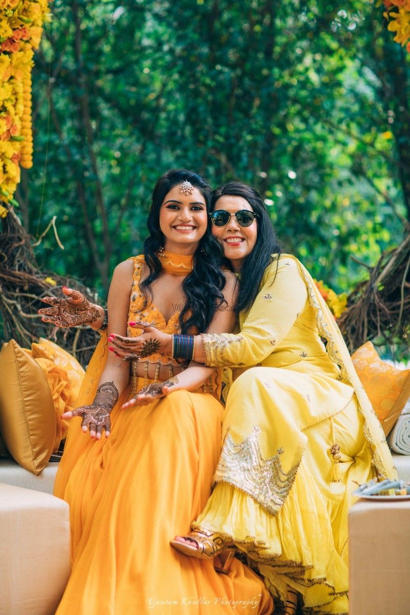Photo of Bride with sister wearing yellow mehendi outfit